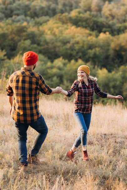 Cheerful guy and girl on a walk in bright knitted hats and plaid shirts - Valokuva, kuva