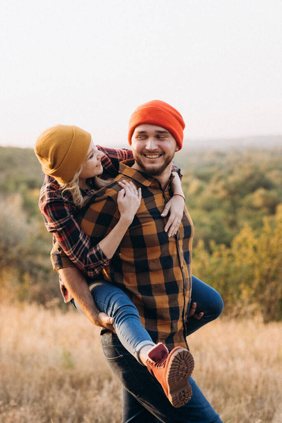 Cheerful guy and girl on a walk in bright knitted hats and plaid shirts - Fotografie, Obrázek