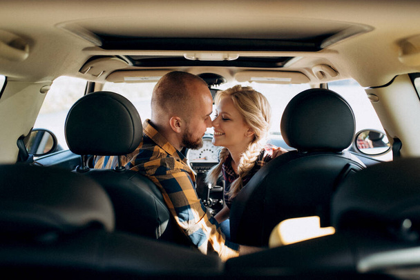 viajando en coche de una joven pareja de un chico y una chica en camisas a cuadros - Foto, imagen