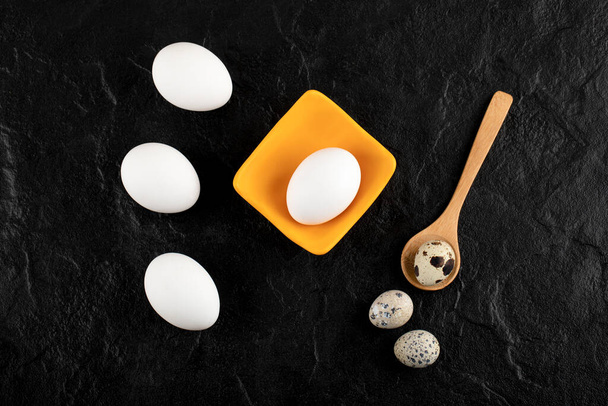 Ovos de codorna e ovos de galinha em fundo preto - Foto, Imagem