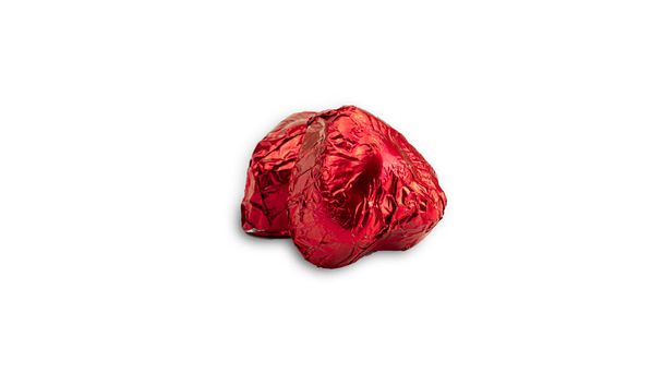 Sweet chocolate heart shaped candy wrapped in red foil papper on white background. High quality photo - Photo, Image