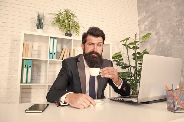 朝ホットカップを飲むのが好きではない人。エンジニアはワークデスクでティーカップを保持します。髭の男はコーヒーを飲むのを楽しむ。エネルギーのための熱い飲み物を飲む。健康的な飲酒習慣。朝食 - 写真・画像