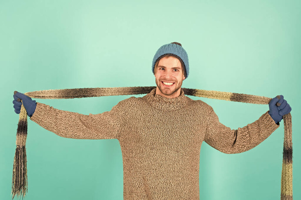 Warm up chilly days with cosy scarf. Happy man wear long scarf. Handsome guy smile with scarf in hands. Fashion accessory for winter. Stylish knit scarf with striped design - Photo, image