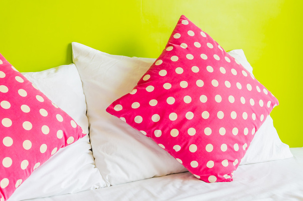 πολύχρωμο, πουά μαξιλάρι σε λευκό κρεβάτι - Φωτογραφία, εικόνα