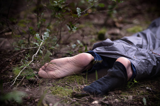 Un cadavre dans les bois. Victime d'un meurtre allongée par terre dans la forêt. Citoyen assassiné, scène de crime - Photo, image