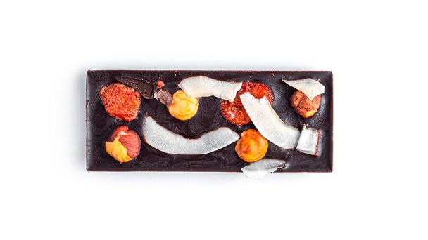 Сырой шоколад с сухофруктами и орехами на белом фоне. Высокое качество фото - Фото, изображение