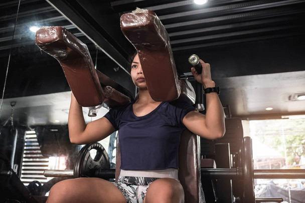 Une jeune femme asiatique athlétique faisant quelques squats hack à la salle de gym. Quads et fessiers d'entraînement. - Photo, image