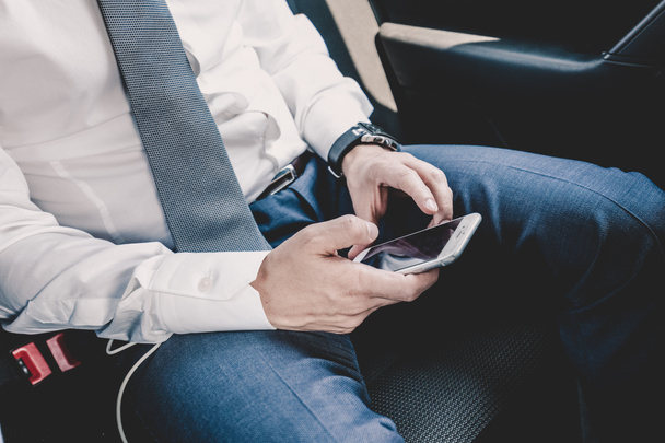 Close-up de homem de negócios usando telefone inteligente móvel em um carro. - Foto, Imagem