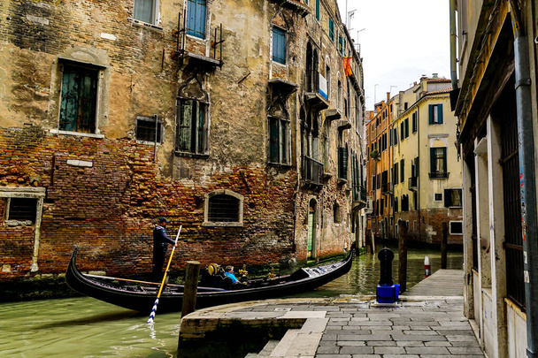 Velence egy gyönyörű napon a kis keskeny csatornák és csónakok és gondolák úszó híd alatt Velence, Olaszország. - Fotó, kép