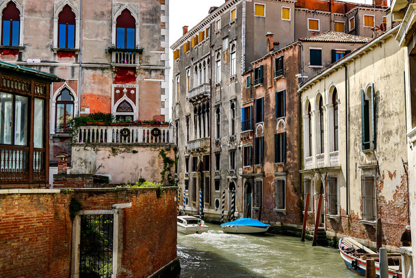 Venice on a beautiful day with small narrow canals and boats and gondolas floating under bridges in Venice, Italy. - 写真・画像