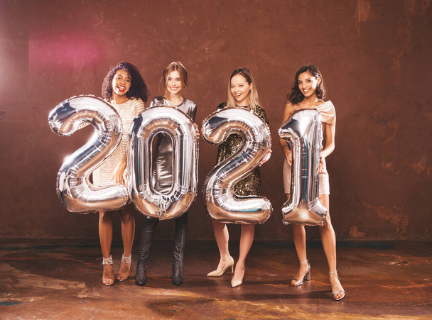 Beautiful Women Celebrating New Year.Happy Gorgeous Female In Stylish Sexy Party Dresses Holding Silver 2021 Balloons, Having Fun At New Year's Eve Party. Holiday Celebration.Charming Models  - Fotó, kép