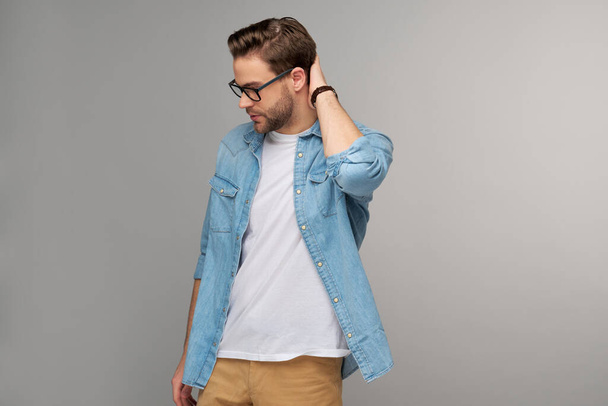 Portrait of young handsome caucasian man in jeans shirt over light background - Foto, afbeelding