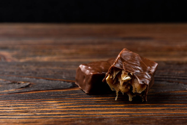 Chocolade zoet met karamel en pinda op donkere houten ondergrond. - Foto, afbeelding