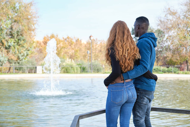Afrikanischer schwarzer Mann und rothaarige kaukasische Frau rückwärts in einem Park. Junge multirassische Paare porträtiert. - Foto, Bild