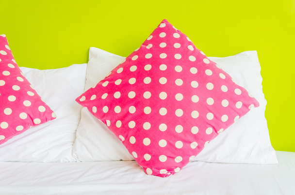 kleurrijke polka kussen op witte bed - Foto, afbeelding