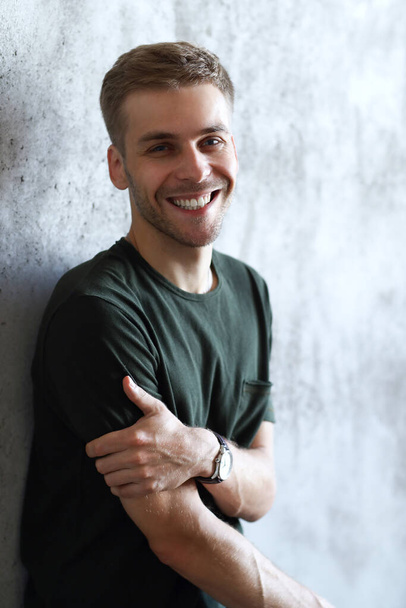 Happy, handsome man on a concrete wall background - Fotoğraf, Görsel