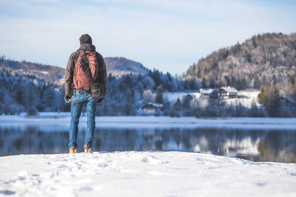 Sporty Caucasian man is at the lakeshore, enjoying the view. Winter landscape. - Foto, Bild
