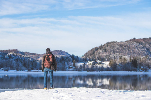 Sporty Caucasian man is at the lakeshore, enjoying the view. Winter landscape. - Foto, Bild