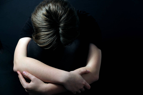 tiener zitten in een gesloten houding ervaren geestelijke gezondheidsproblemen zoals depressie tijdens COVID-19 lockdown - Foto, afbeelding