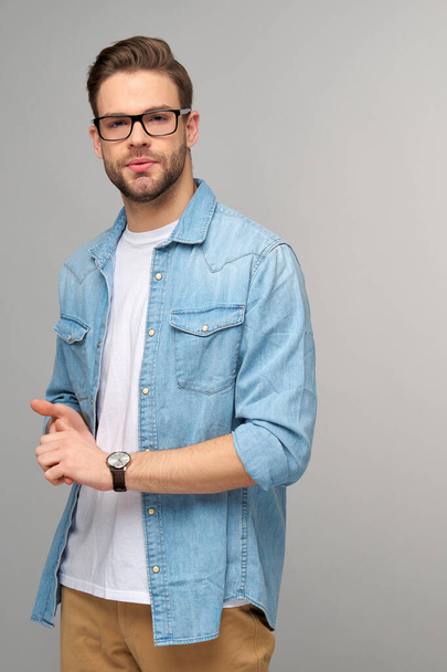Portrait of young handsome caucasian man in jeans shirt over light background - Фото, зображення