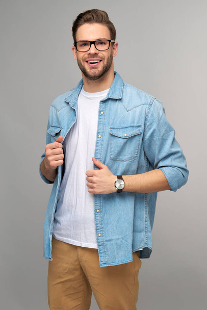 Portrait of young handsome caucasian man in jeans shirt over light background - Fotó, kép