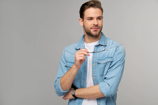 Portrait of young handsome caucasian man in jeans shirt over light background - Valokuva, kuva