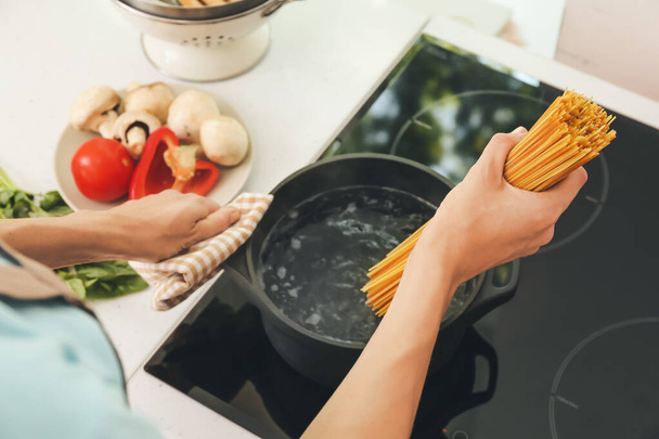 Woman cooking pasta on electric stove - Фото, зображення