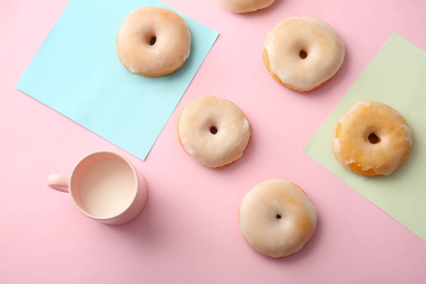 Maukkaita donitseja ja kuppi maitoa värillisellä taustalla - Valokuva, kuva