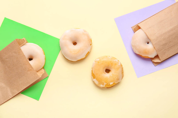 Tasty donuts in paper bags on color background - Photo, Image