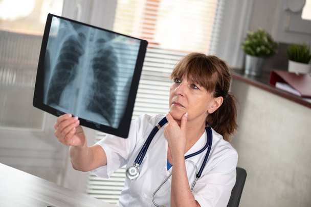 Médica examinando relatório de raio-x em consultório médico - Foto, Imagem