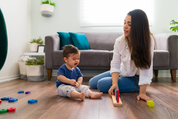 赤ちゃん男の子座っている床と泣いている間におもちゃと一緒に母でリビングルーム - 写真・画像