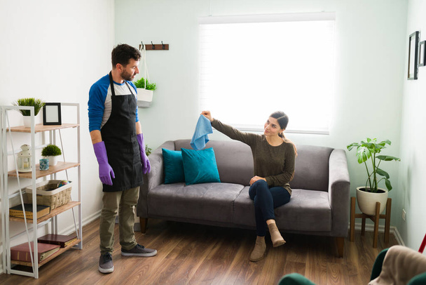 Vista completa di una moglie esigente che consegna un panno di pulizia al suo partner per far pulire la casa - Foto, immagini