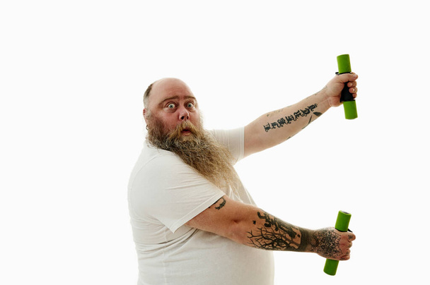 Портрет з боку ожиріння людини, що займається з гантелями, виражаючи сюрприз
. - Фото, зображення