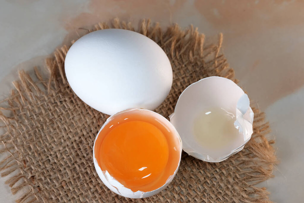 Білі сирі яйця лежать на столі на мішковині крупним планом макрозйомка
 - Фото, зображення