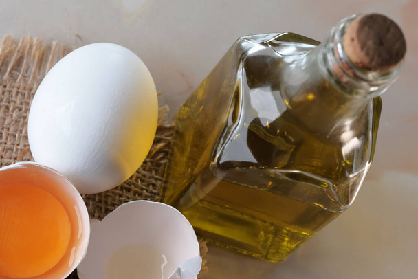 White raw eggs lie on the table next to olive oil for making mayonnaise close-up macro photography - Zdjęcie, obraz