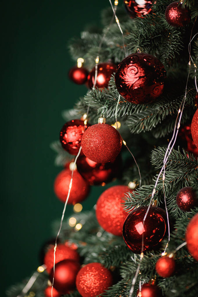 Red balls decorate a Christmas tree on a green background. Selective focus. - Foto, Imagem