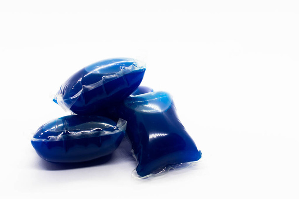 Gros plan de comprimés de détergent pour lave-linge bleu très vif isolés sur un fond blanc - Photo, image