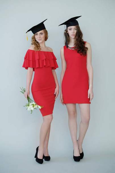 Afgestudeerd. Twee mooie vrouwen in rode jurk - Foto, afbeelding
