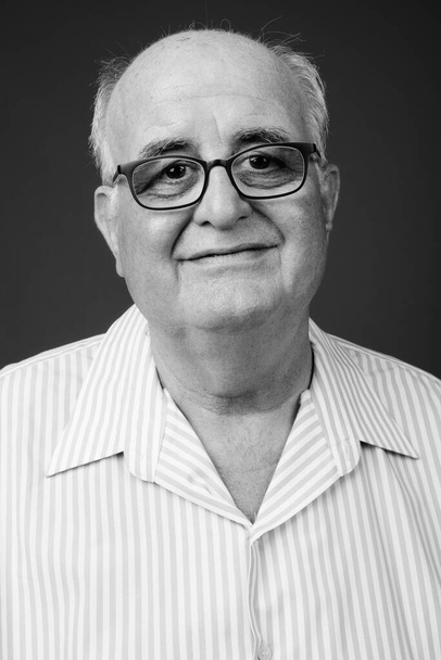 Studio shot of overweight senior man wearing eyeglasses against brown background - Фото, зображення