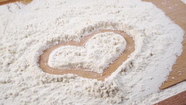心のシンボルは、切削板の上に小麦粉に描かれています。閉めろ。ドリーは撃たれた。愛の概念 - 映像、動画