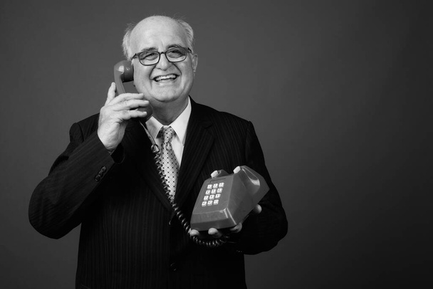 Studio záběr nadváhy starší podnikatel nosí brýle proti hnědému pozadí - Fotografie, Obrázek