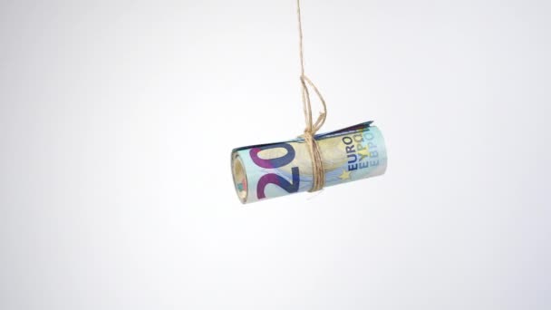 Rouleau de billets en euros attaché avec une corde de jute et suspendu et séchant sur un fond blanc. Ferme là. Concept de blanchiment d'argent criminel - Séquence, vidéo
