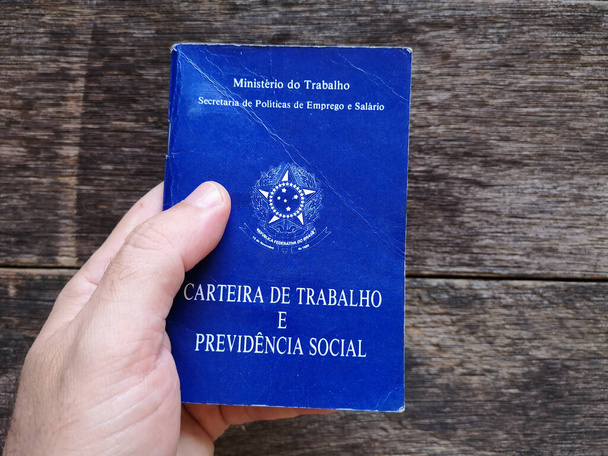 Tenuta in mano documento brasiliano lavoro e sicurezza sociale con sfondo in legno - Foto, immagini