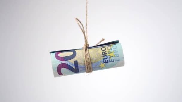 Válcované eurobankovky svázané jutovým provazem a visící na bílém pozadí zblízka. Koncept praní špinavých peněz a finanční trestné činnosti - Záběry, video