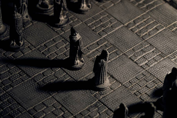 Porträt zweier Soldatinnen einer Schachpartie, die sich zu Beginn des strategischen Matches gegenüberstehen. Das Schachbrett und die Armeeteile sind aus Stein für das Duell. - Foto, Bild