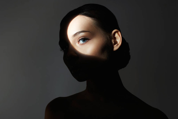 Silhouette eines schönen Mädchens in der Dunkelheit. junge Frau mit Schatten im Gesicht - Foto, Bild