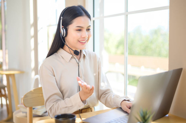 Een vrouw van de klantenserviceoperator in de headset met behulp van een computer die de oproep beantwoordt op kantoor - Foto, afbeelding