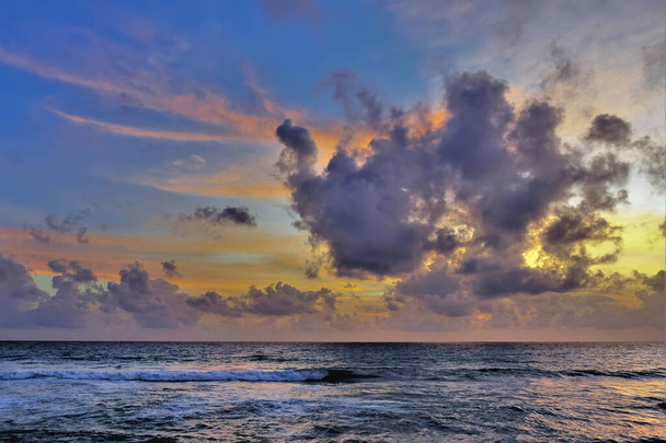 Fantastico tramonto sull'Oceano Indiano. Il cielo blu è retroilluminato di rosa e oro. Nuvole lilla stravaganti. Onde con schiuma sulla superficie turchese dell'acqua. Sri Lanka. - Foto, immagini