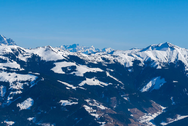 Uitzicht op de besneeuwde bergen in het skigebied Schmitten in Zell am See. Op de achtergrond is een prachtige lucht met wolken. - Foto, afbeelding