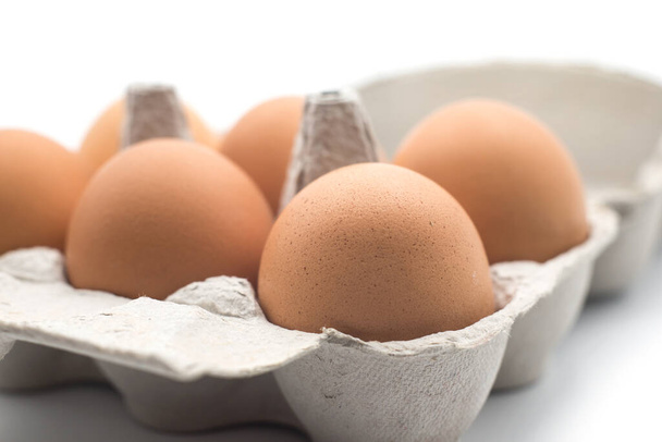 Closeup of organic eggs in a grey carton box on white background - Foto, Imagen